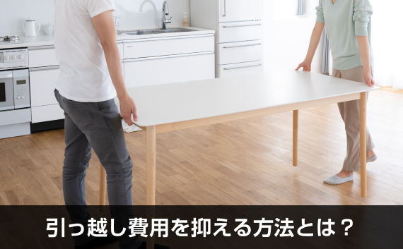 写真：引っ越し費用を抑える方法とは？。机を2人で運んでいる写真。