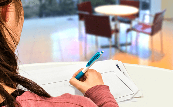 写真：車・バイクの引越し後に必要な手続き。紙に何かを書いている女性の手。