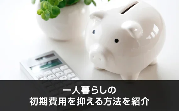 写真：一人暮らしの初期費用を抑える方法を紹介。豚の貯金箱と電卓が写っている写真。