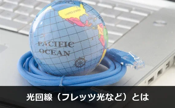 写真:光回線(フレッツ光など)とは。ノートPCの上に小さい地球儀とケーブルがのっている写真。