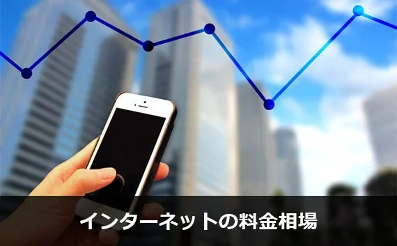 写真:インターネットの料金相場。スマホとグラフに背景がビルのイメージ画像。