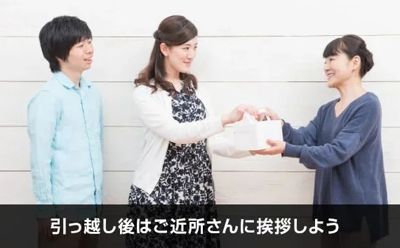 写真：引っ越し後はご近所さんに挨拶しよう。女性が贈り物を渡して挨拶している写真。