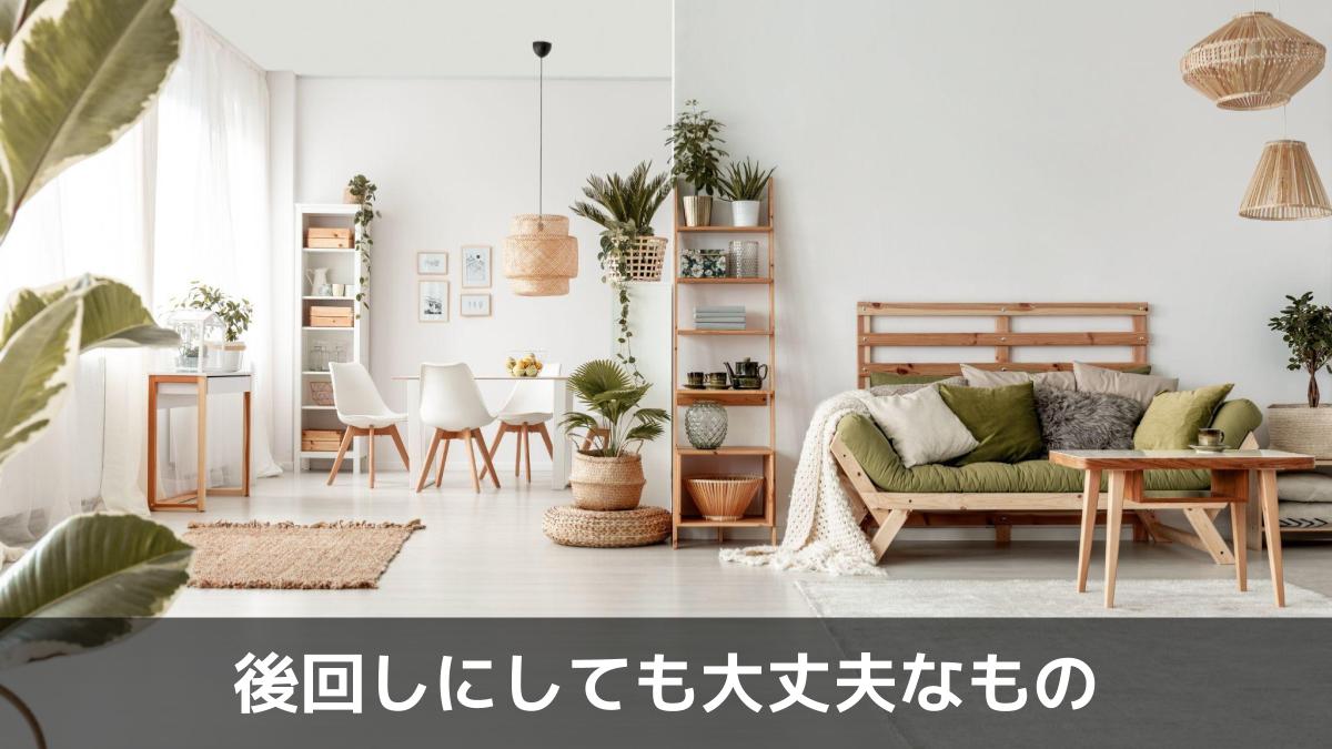 写真：後回しにしても大丈夫なもの。広々としたリビングルームのインテリア。植物とランプが置かれた緑のソファの前に置かれた木製のテーブル。