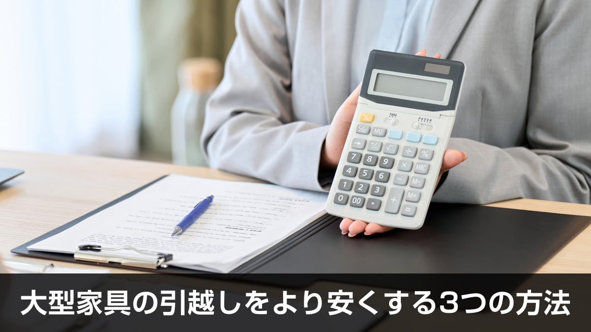 電卓を持っている女性の手と、書類が置かれたデスク