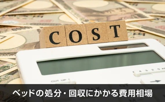 写真：ベッドの処分・回収にかかる費用相場。COSTと書かれたコルクのオブジェと電卓とお札が写っている写真。