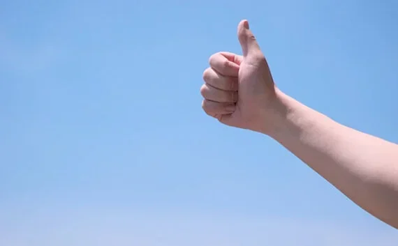 写真：空に向かってグッドの手のポーズをする写真