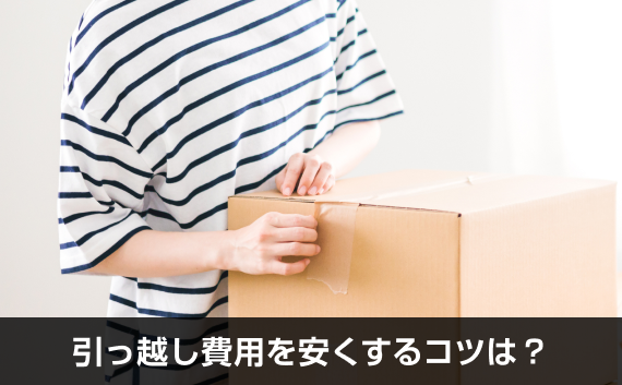 写真：引っ越し費用を安くするコツは？。ガムテープが貼られたダンボールに手を添えている様子の写真。