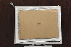 写真：モニターの液晶画面にタオルをあててダンボールで固定している写真