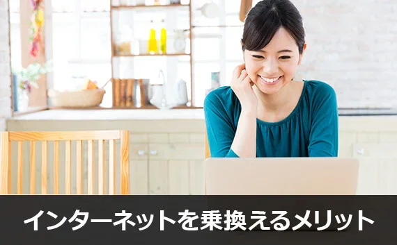 写真：インターネットを乗換えるメリット。笑顔の女性がノートPCを見ている写真。