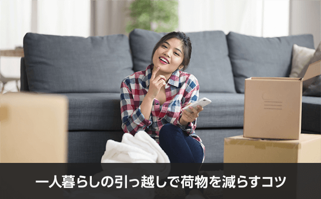 写真：一人暮らしの引っ越しで荷物を減らすコツ。女性がスマホをもって首を傾げている写真。