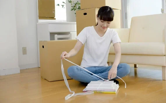 写真：本を紐でまとめている女性の写真。