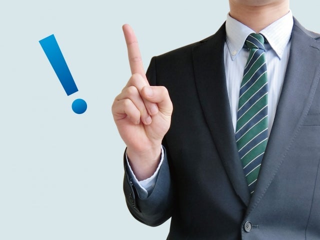 写真：敷金礼金なし物件に引越しする2つのメリット。人差し指を立てているスーツの男性の写真。