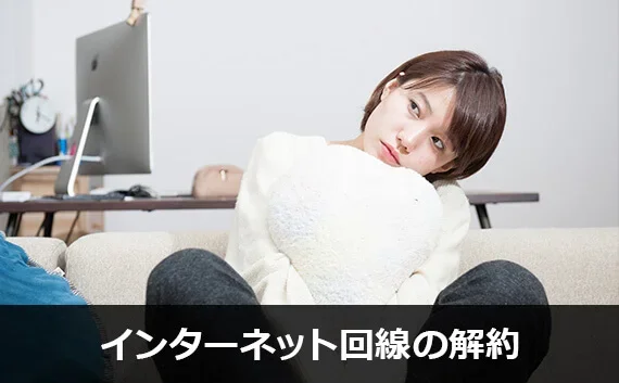 写真：インターネット回線の解約。枕を抱えた女性が座っている写真。