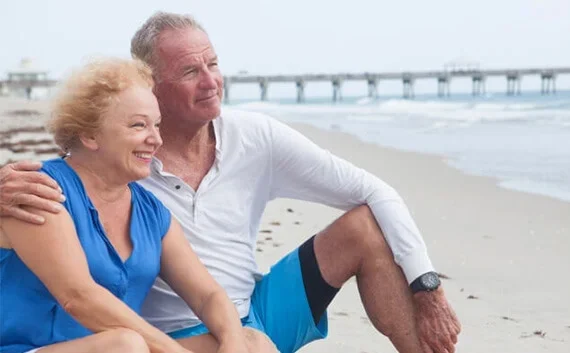 写真：シニアの夫婦が浜辺に座っている写真。