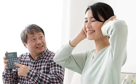 写真：引っ越し業者ごとの見積もり料金を比較する。電卓を持った男性と耳を塞いでいる女性の写真。