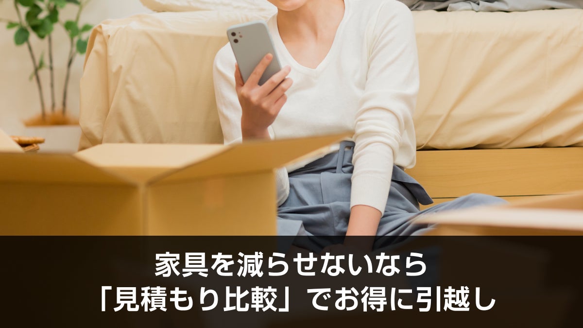 段ボール箱の近くでスマートフォンを持って座っている人物