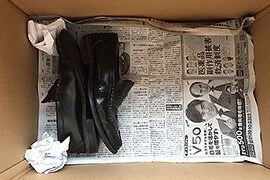 写真：ダンボール箱に靴を詰めて引越しをする場合。段ボールに靴を収納している様子。