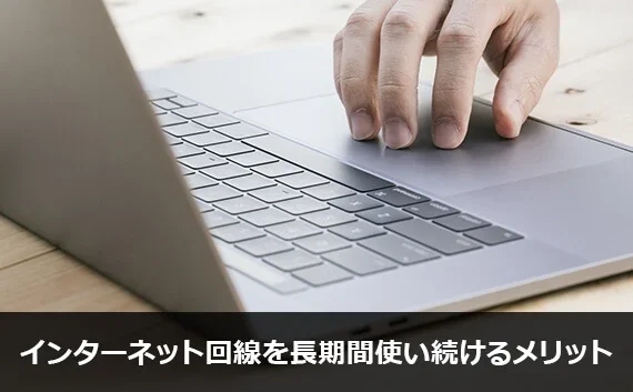 写真：インターネット回線を長期間使い続けるメリット。ノートPCと手が写っている写真。