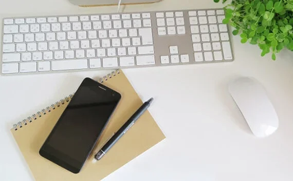 写真:ノート・スマホ・ペン・キーボード・マウスが写っている写真。