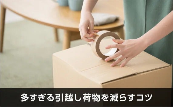 写真：多すぎる引越し荷物を減らすコツ。段ボールの蓋を閉めている手。