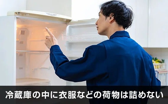 写真：冷蔵庫の中に衣服などの荷物は詰めない。冷蔵庫の中身を確認する作業員