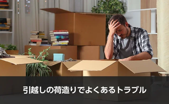 写真:引越しの荷造りでよくあるトラブル。ダンボールの前で頭を抱えている男性の写真。