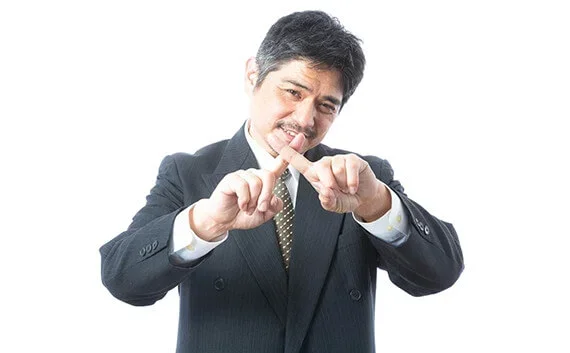 写真：人差し指で罰印を作っている男性の写真