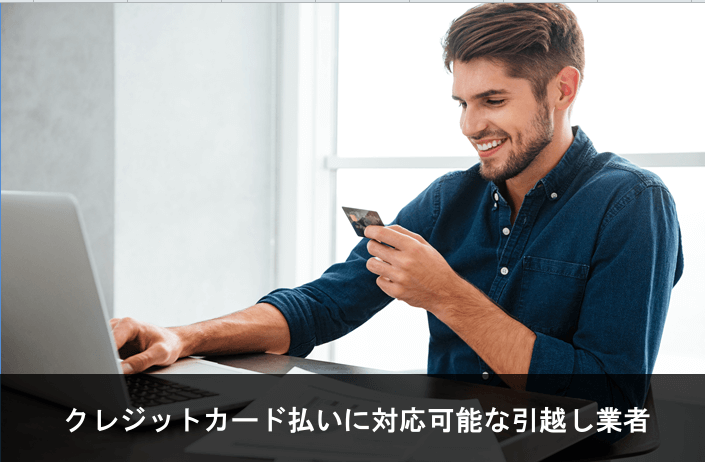 写真：クレジットカード払いに対応可能な引越し業者。クレジットカードとノートPCを手に笑顔の男性の写真。