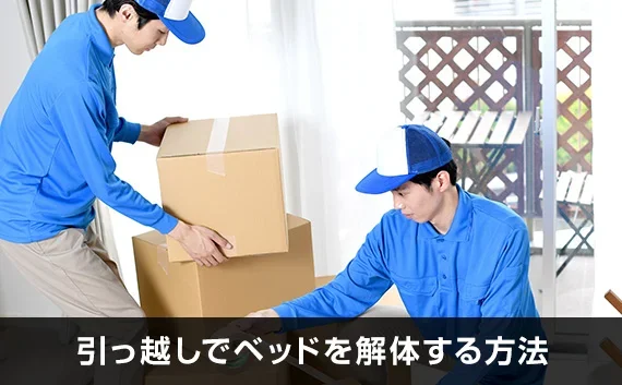 写真：引っ越しでベッドを解体する方法。2人の業者がダンボールを運んでいる写真。