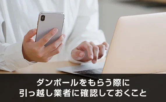 写真：ダンボールをもらう際に引っ越し業者に確認しておくこと。ノートPCとスマホを持っている人の写真。