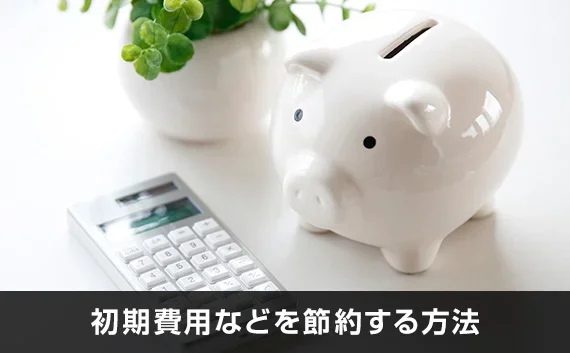 写真：初期費用などを節約する方法。豚の貯金箱と電卓が写っている写真。