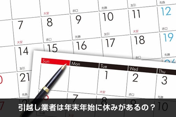 重ねて置かれているカレンダーの上に黒いボールペンが置かれている様子