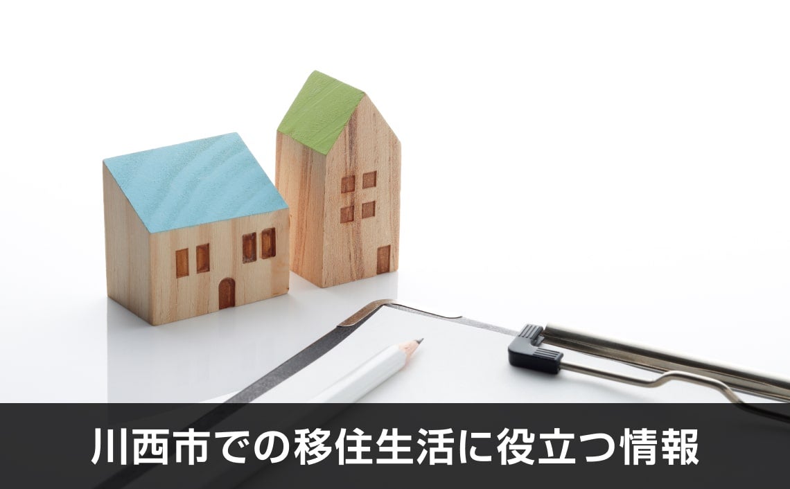 写真：川西市での移住生活に役立つ情報。木のオブジェとバインダーと鉛筆が写っている写真。