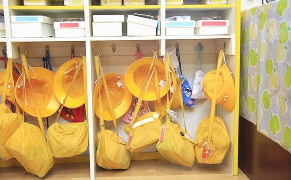 ロッカーにかけられた保育園の黄色い帽子と通園バッグ