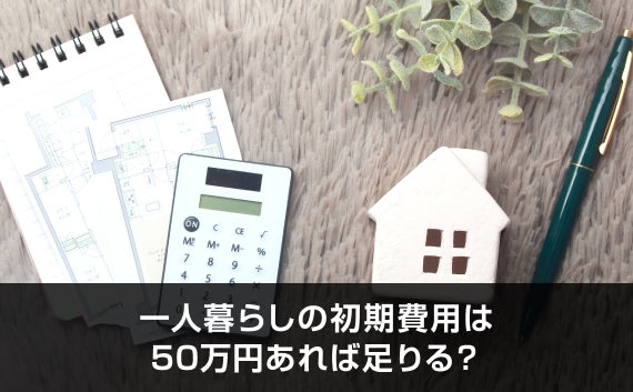 写真：一人暮らしの初期費用は50万円あれば足りる？。電卓と家のオブジェが置いてある机の写真。